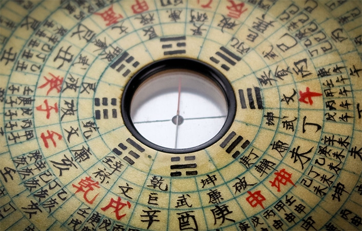 a traditional Chinese astrological compass with red and black Chinese characters on it