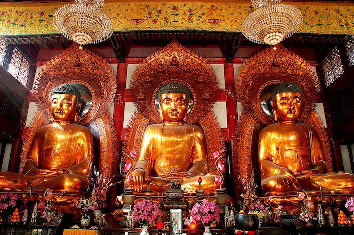 three Buddhist statues in a temple