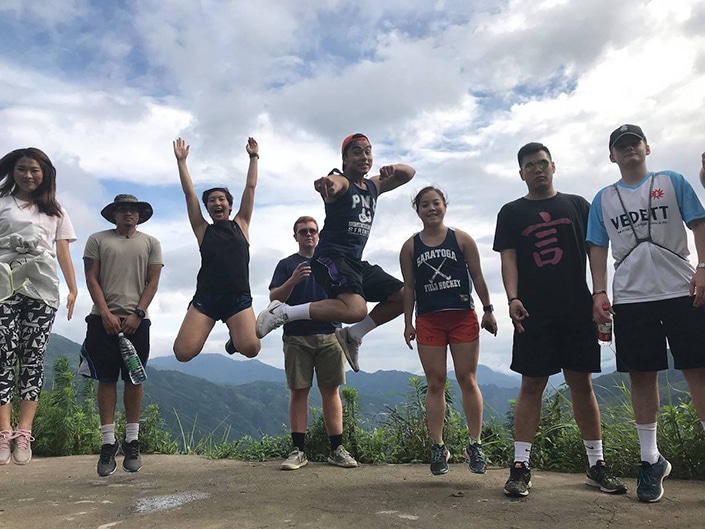 CLI students jump into the air with mountains in the background