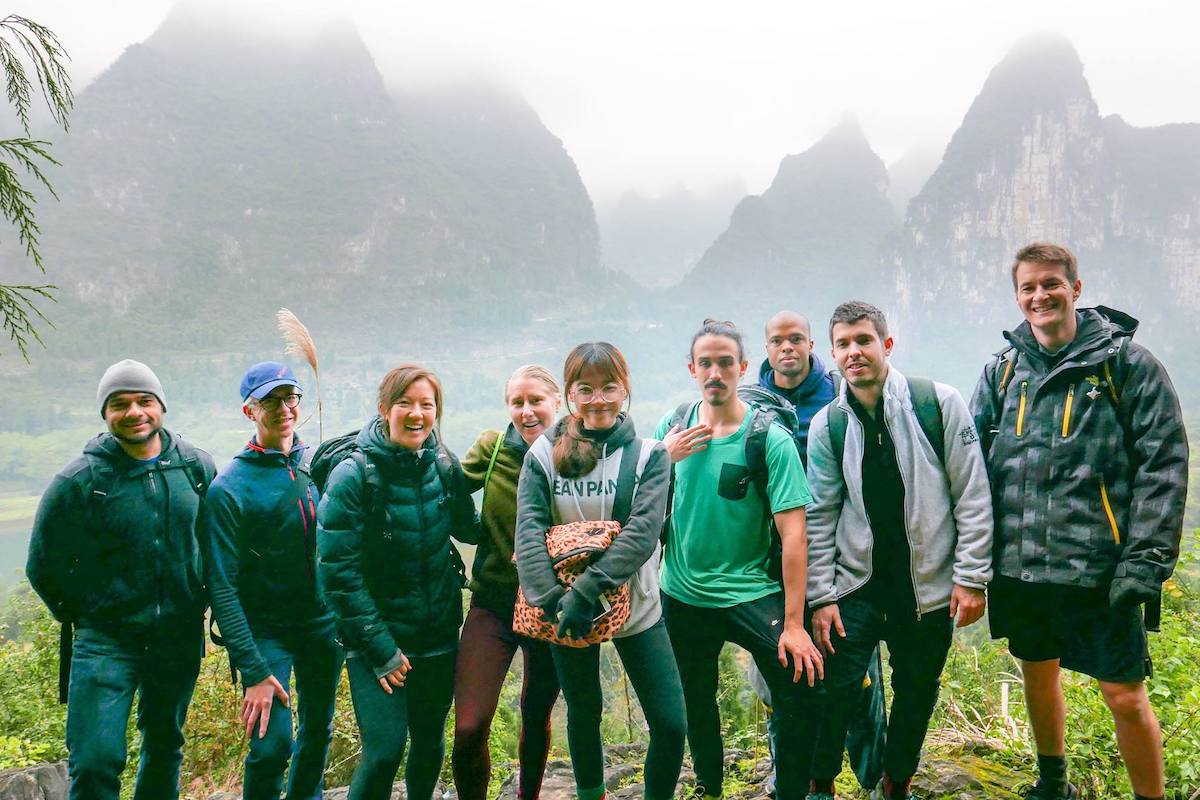 A group of CLI students and Yangshuo travel guides stand in front of karst mountains