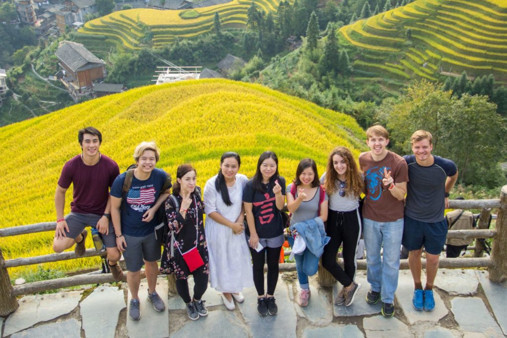 A group of CLI students pose with yellow rice terraces in the background