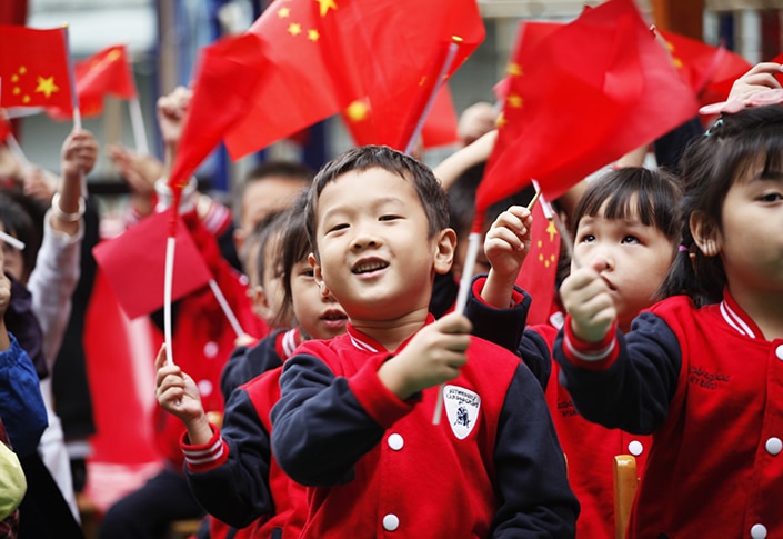 a photo of Chinese children waving red Chinese flags on National Day, an important Chinese holiday