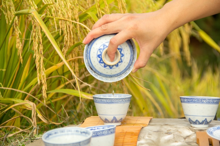 a hand pouring traditional Chinese tea from a gaiwan teapot