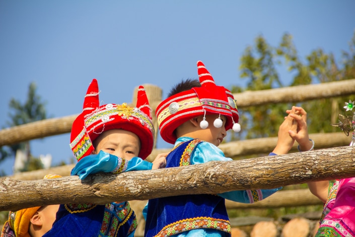 Two Chinese children wear traditional ethnic minority hats and clothes