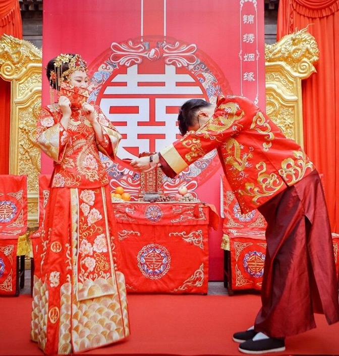 a bride and groom in traditional red and gold dress during a traditional Chinese wedding ceremony