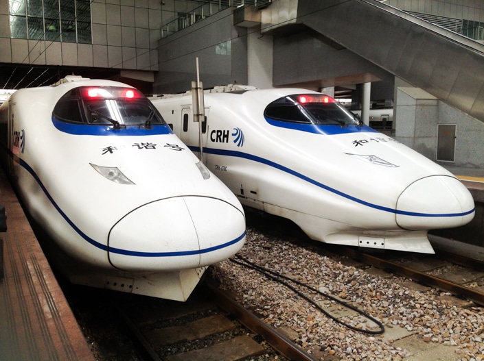 two Chinese fast trains sitting at a station