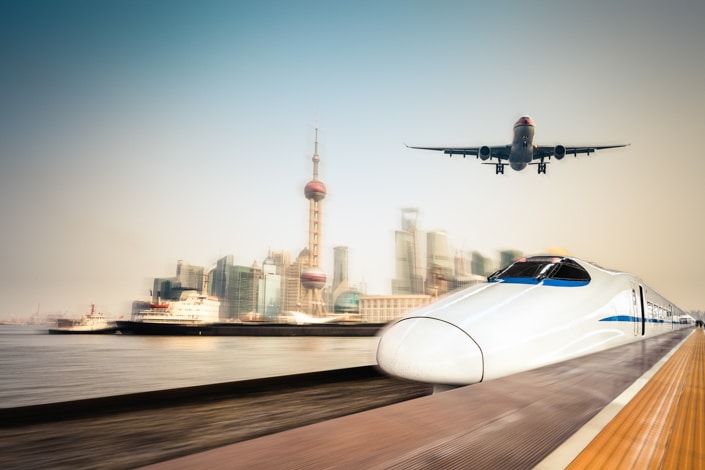 a Chinese fast train and airplane in the foreground with the Shanghai skyline in the background