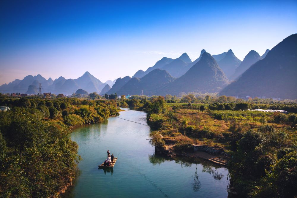 a Yangshuo travel guide and visitors rafting on the Yulong River with karst peaks