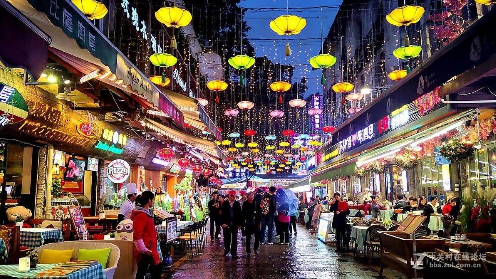 Yangshuo travel guides and visitors walk along Xi Jie in Yangshuo at night with yellow lanterns hanging above them