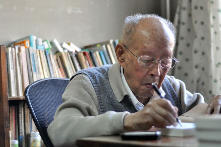 Zhou Youguang, the father of pinyin, writing at a desk