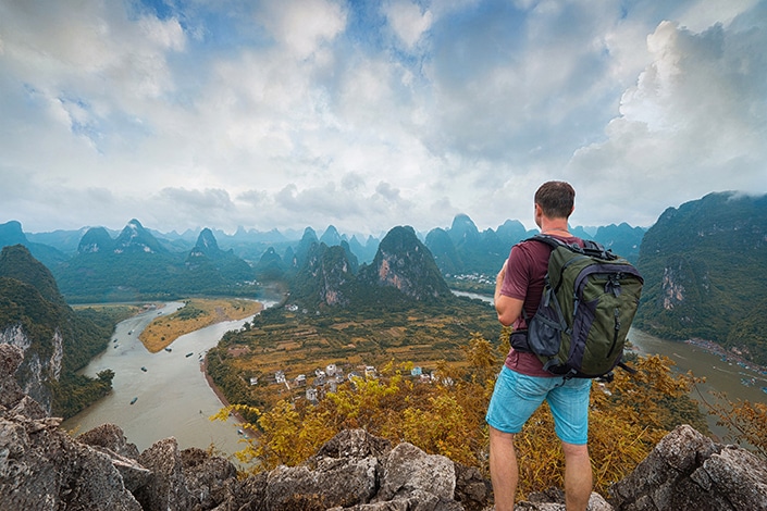 a hiker serving as his own Yangshuo travel guide looks out at a forest of karst mountains