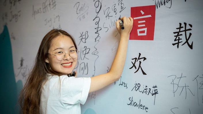 a CLI teacher writing Chinese characters on a wall