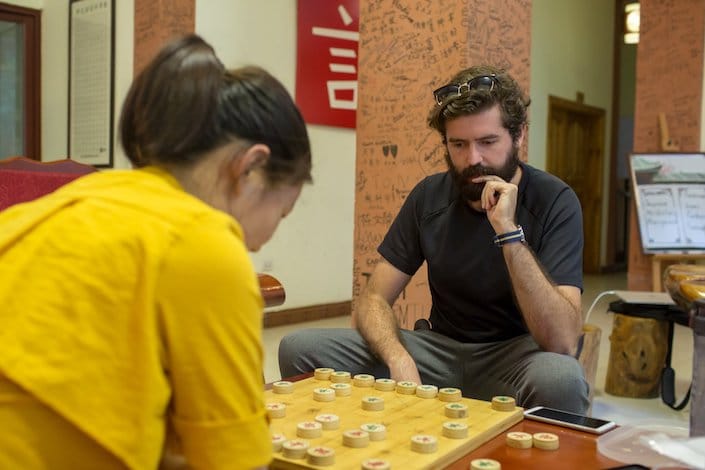 a male and female student playing Chinese chess