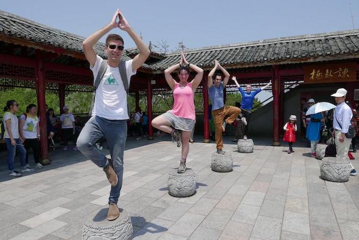 four CLI students posing on top of carved stones in China