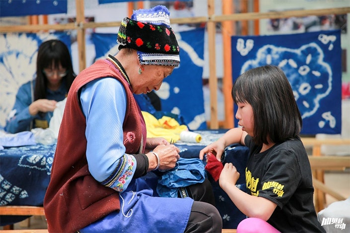 a ethnic minority woman works with cloth as a child looks on