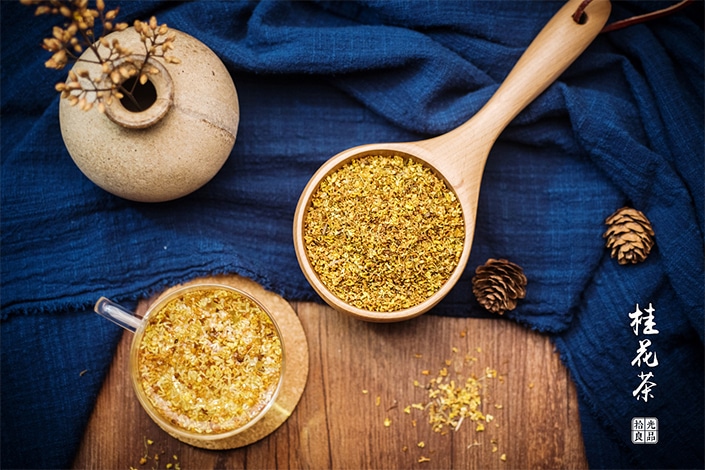 a wooden spoon and glass teapot full of osmanthus flowers