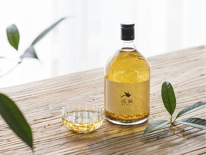 a bottle and cup of osmanthus wine sitting on a wooden table