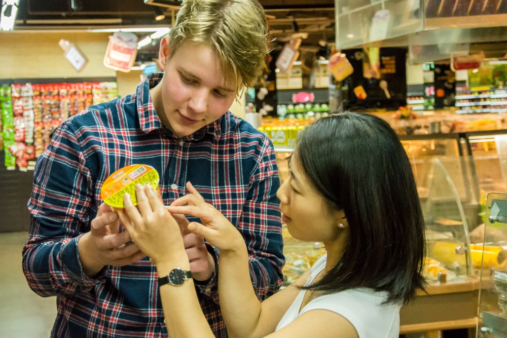 a student and teacher examine an item while shopping in a Chinese supermarket