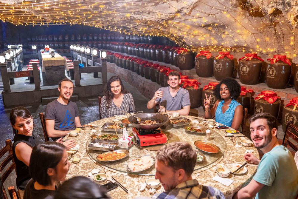 students sit around a table of food in a cave in Guangxi, China