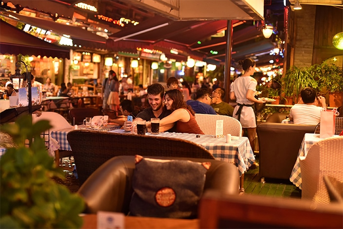 a man and woman sit at a table at an outdoor restaurant