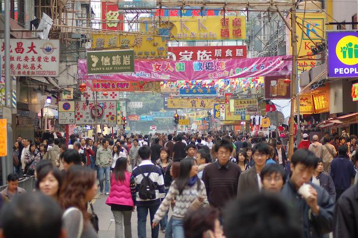 Hong Kong street scene showing a busy shopping street full of people with colorful banners strung across the street