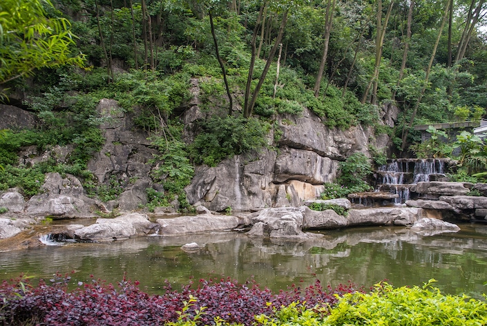 a small water fall trickling into a pond in Seven Star Park, Guilin, China