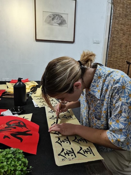 a woman with blonde highlights practicing Chinese calligraphy at CLI in Guilin, China