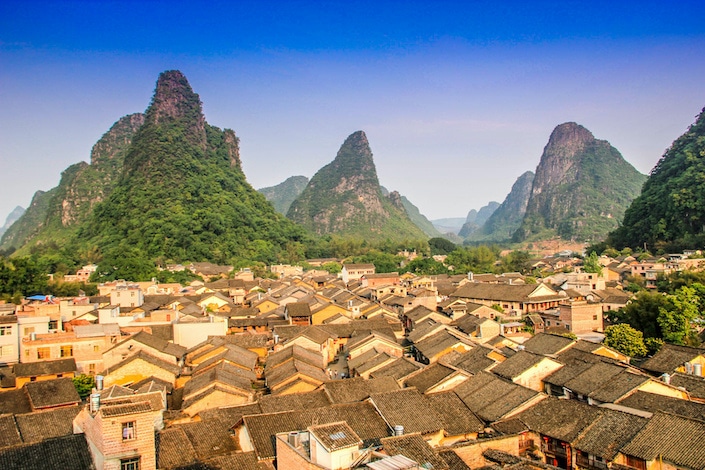a village with traditional Chinese houses flanked by karst mountains in Guangxi Province, China