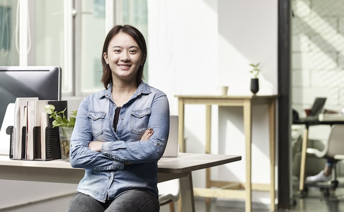 portrait of a young asian business woman looking at camera smiling arms crossed