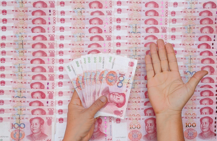 chinese currency neatly spread out on table with person's open hand above