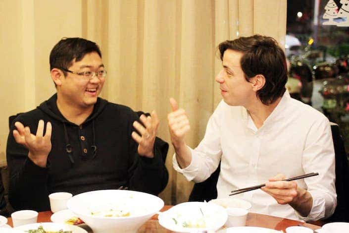 western man and chinese man chatting while eating dinner