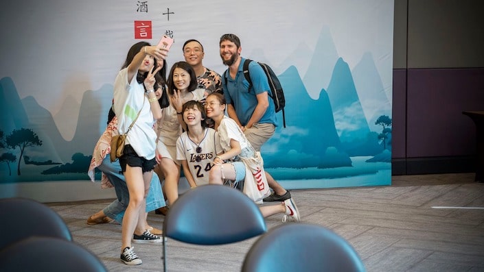 group of young professional taking selfie in front of a backdrop with silhouette of karst mountains