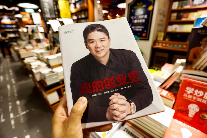 man holding book in Chinese bookstore of Liu Qiangdong