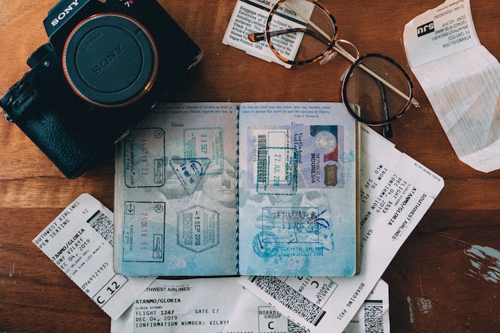 passport, camera, plane tickets and eyeglasses on wooden table