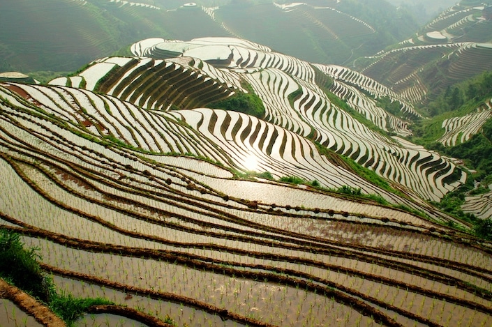 the sun reflecting off of flooded rice fields in Longsheng, China