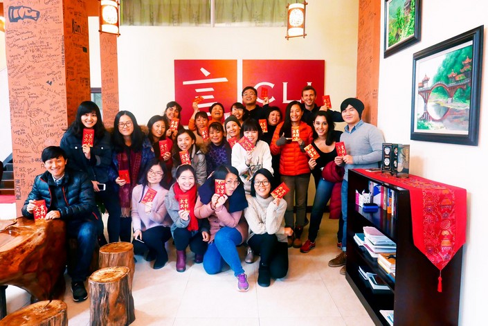 a group of Chinese and western young people holding up chinese red envelopes in front of the CLI sign