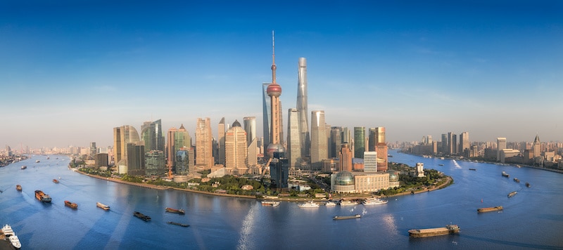 Shanghai skyline with modern urban skyscrapers and ships circling Pundong while sailing the Huangpu River