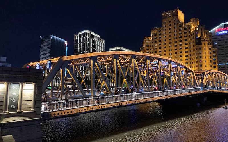 a view of the historical Waibaidu Bridge near the Shanghai Bund at night