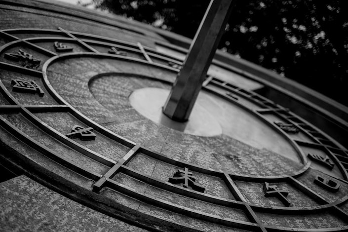 black and white closeup photo of a Chinese sundial with Chinese characters on it